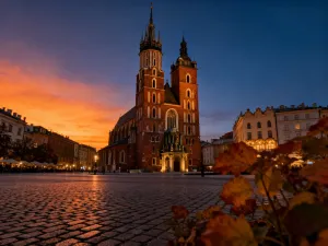 Historyczny drewniany most kolejowy nad rzeką Kwai w świetle zachodzącego słońca z postacią w stroju z lat 40. na brzegu.